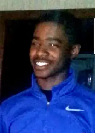 A picture of a young black man, smiling, wearing a track suit.