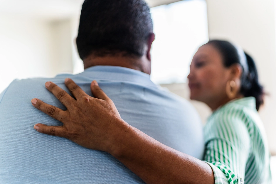 a lady offering support to a man by placing her hand on his shoulder
